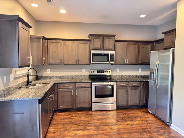a kitchen with stainless steel appliances granite countertop a sink stove microwave and refrigerator