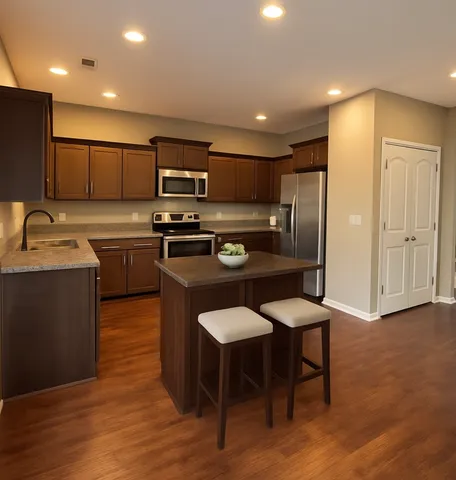 a kitchen with stainless steel appliances granite countertop a sink a stove a refrigerator cabinets and chairs