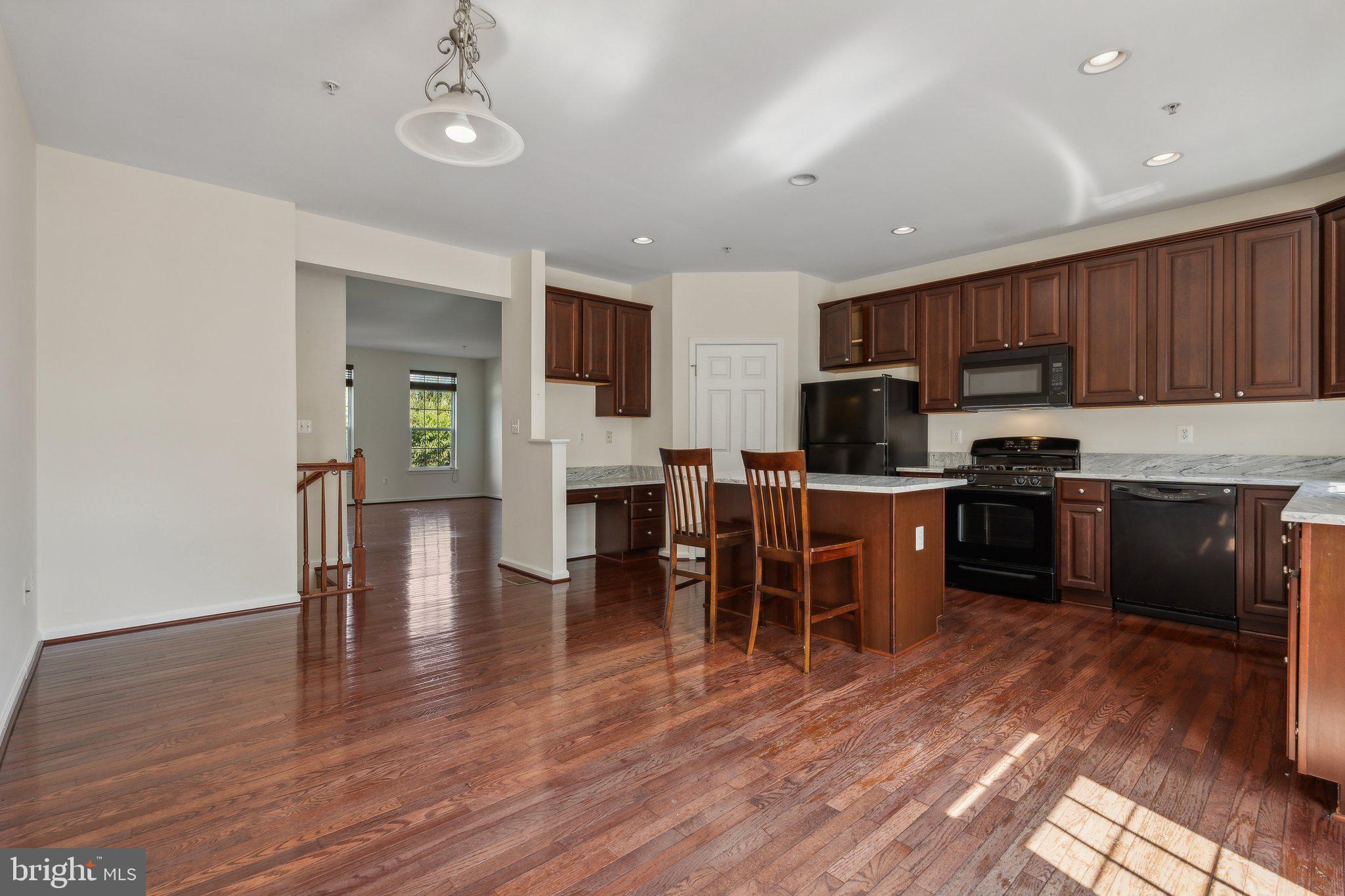 6912 Red Clay Forge, Unit 2 Elkridge, MD 21075 - Photo 5 of 46 a kitchen with stainless steel appliances granite countertop a refrigerator a stove top oven a sink dishwasher a dining table and chairs with wooden floor