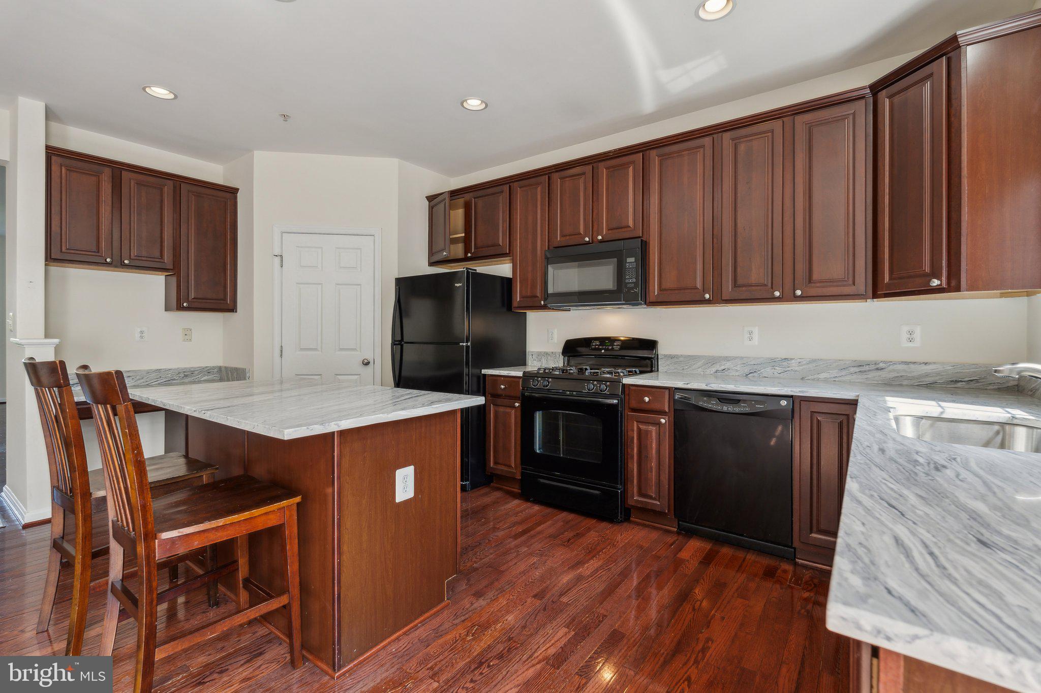 6912 Red Clay Forge, Unit 2 Elkridge, MD 21075 - Photo 6 of 46 a kitchen with granite countertop wooden floors a stove and a refrigerator