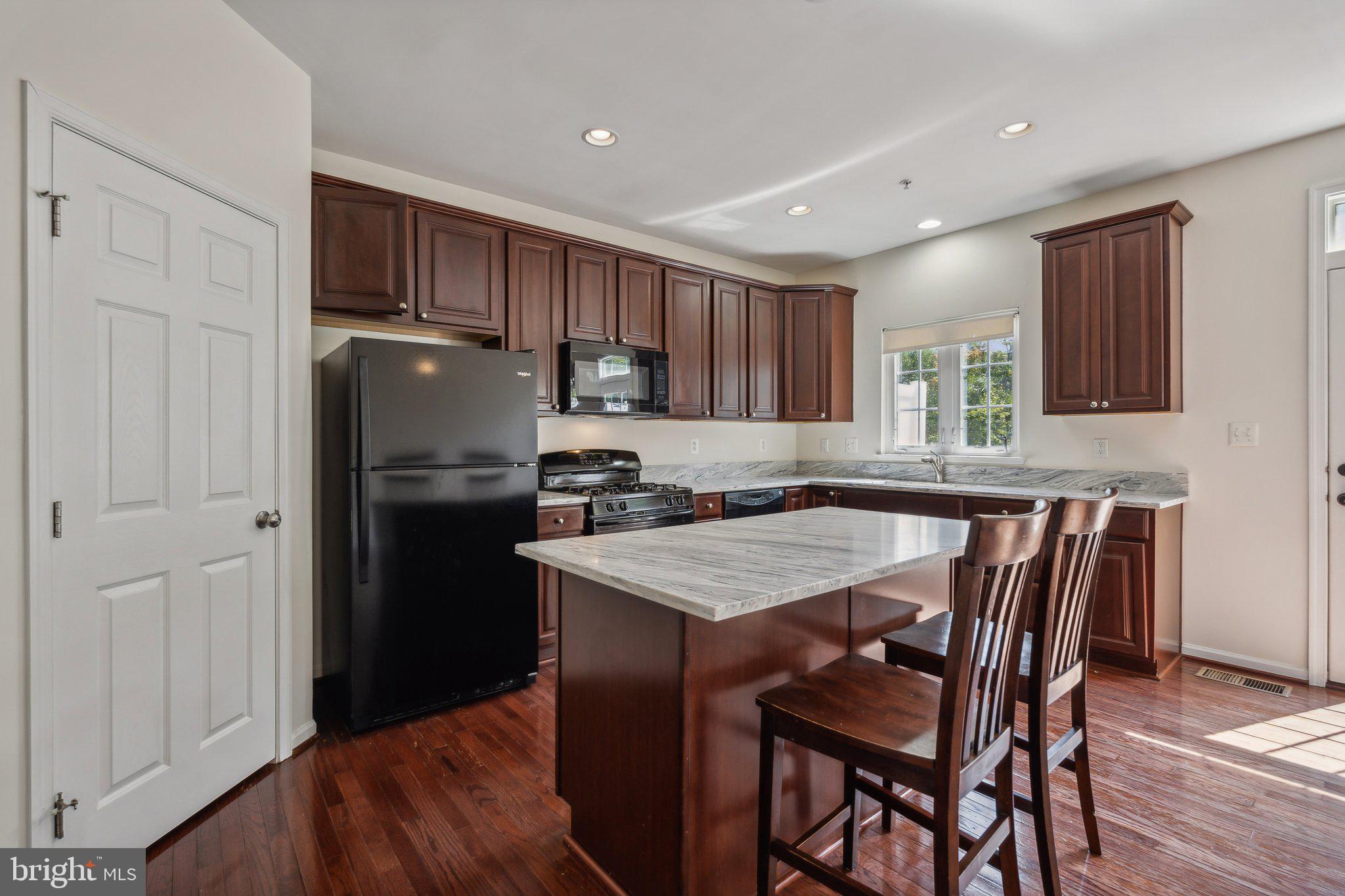 6912 Red Clay Forge, Unit 2 Elkridge, MD 21075 - Photo 7 of 46 a kitchen with a table chairs refrigerator and microwave