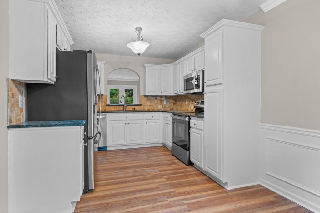 3525 Magnolia Walk Trail Cumming, GA 30040 - Photo 4 of 31 a kitchen with stainless steel appliances granite countertop a refrigerator a sink dishwasher a stove and white countertops with wooden floor