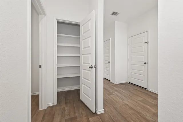 a view of an empty walk in closet with wooden floor