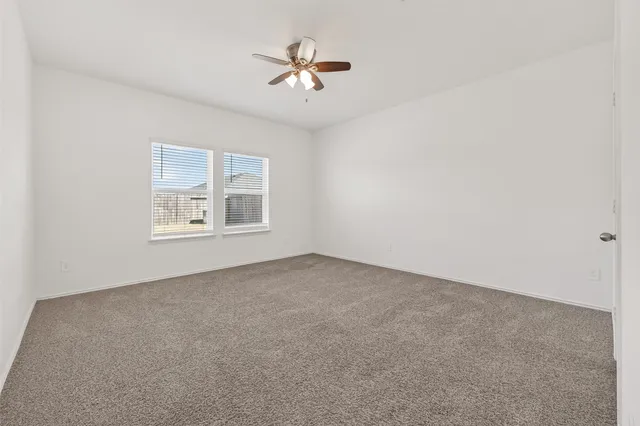 an empty room with windows and ceiling fan
