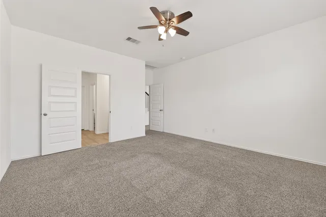 an empty room with closet and a ceiling fan