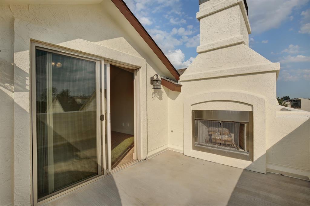 4111 Rawlins Street, Unit 403 Dallas, TX 75219 - Photo 21 of 23 Outdoor balcony featuring a stucco exterior fireplace with a stainless steel insert and glass sliding doors providing interior access