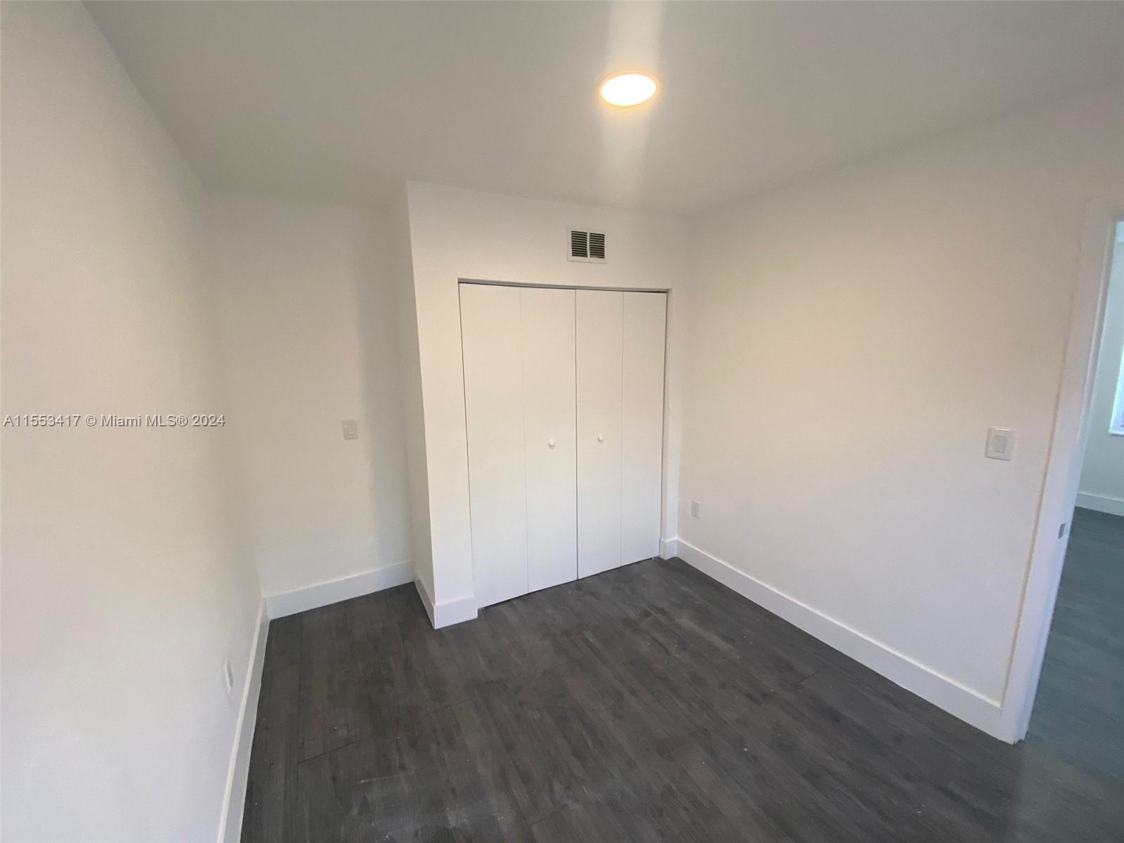 an empty room with wooden floor and white walls