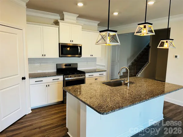 a kitchen with granite countertop a sink a counter top space appliances and cabinets