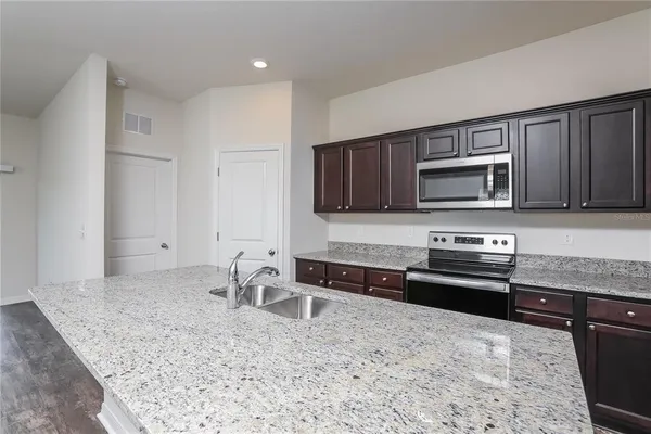 a kitchen with stainless steel appliances granite countertop a stove microwave and sink
