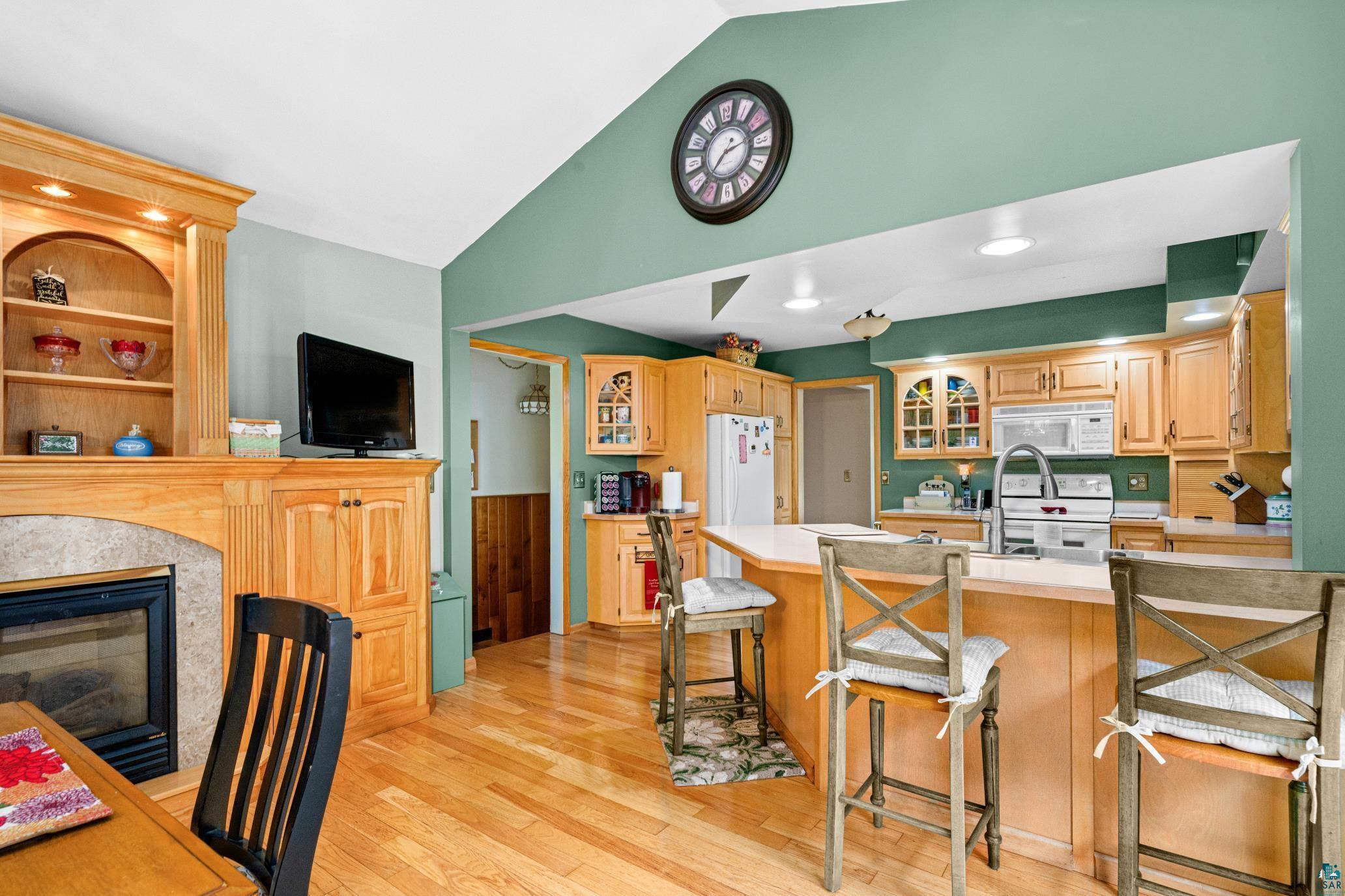 3727 Stebner Road Hermantown, MN 55811 - Photo 13 of 41 Hardwood flooring, fireplace with built-in cabinetry, vaulted ceiling, recessed lighting, and a kitchen island with seating