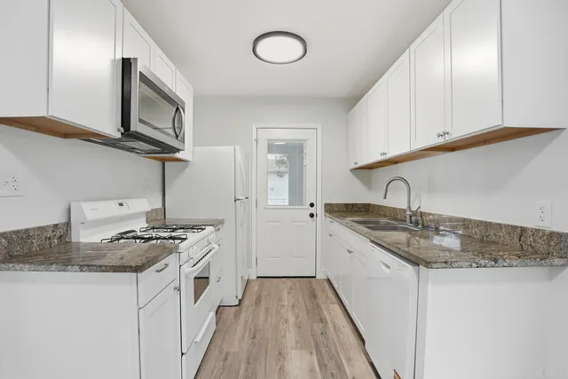 a kitchen with granite countertop a sink stove and cabinets