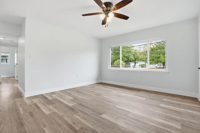 a view of an empty room with wooden floor and a window