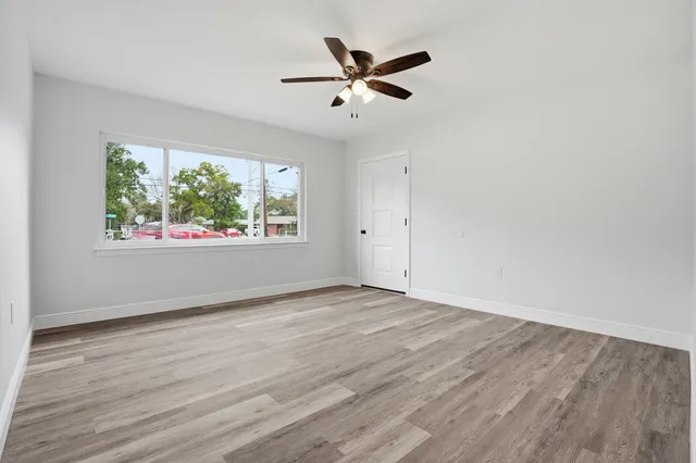 an empty room with wooden floor and windows