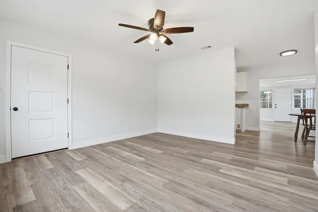 a view of empty room with wooden floor and ceiling fan