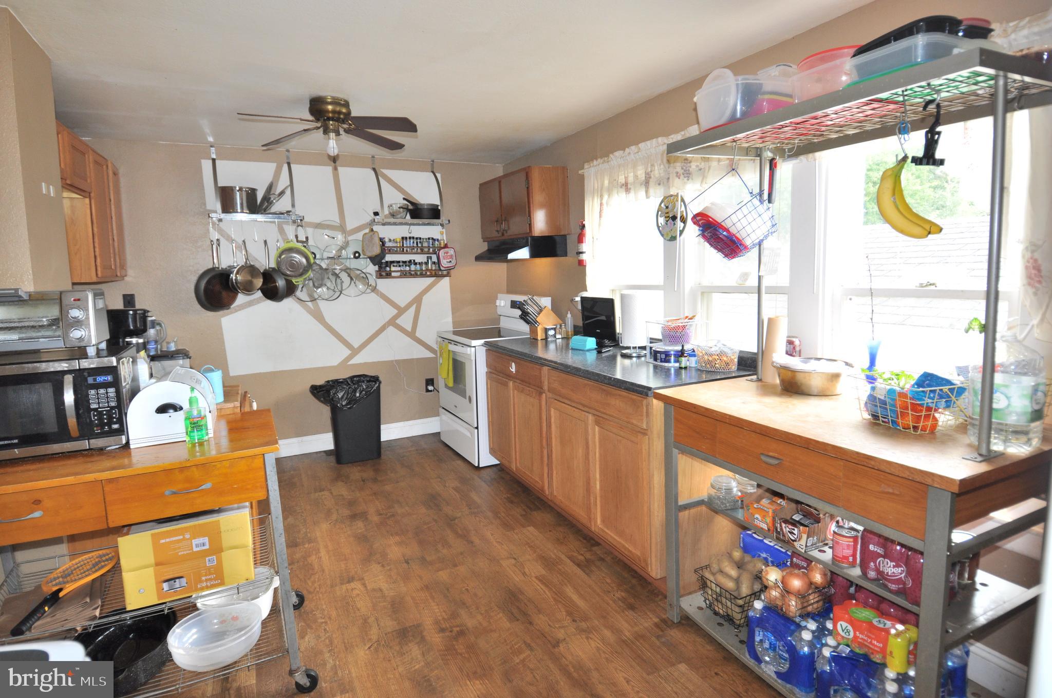 105 Front Street Pocomoke City, MD 21851 - Photo 11 of 50 a kitchen with stainless steel appliances a sink dishwasher and a dining table with wooden floor