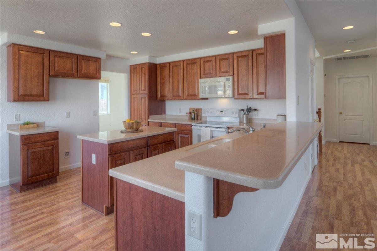 10016 Cascade Falls Drive Reno, NV 89521 - Photo 14 of 40 a kitchen with stainless steel appliances granite countertop a sink a stove a refrigerator and a microwave with wooden floor