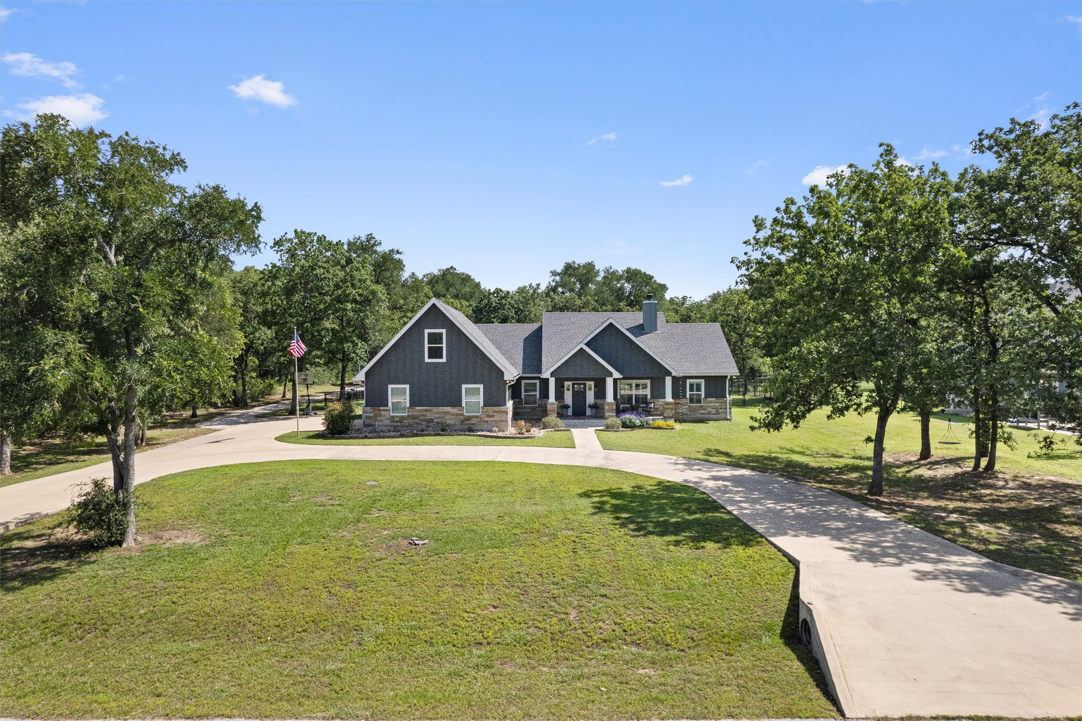 136 Fawn Hollow Elgin, TX 78621 - Photo 3 of 40 Contemporary ranch-style residence featuring dark siding with stone accents, a multi-gabled roofline, and a prominent chimney