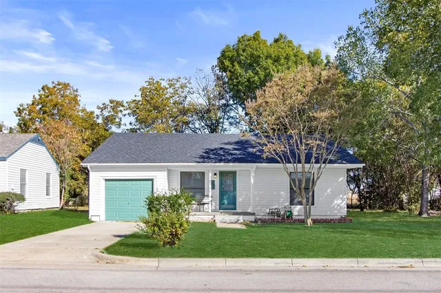 a front view of a house with a garden and trees