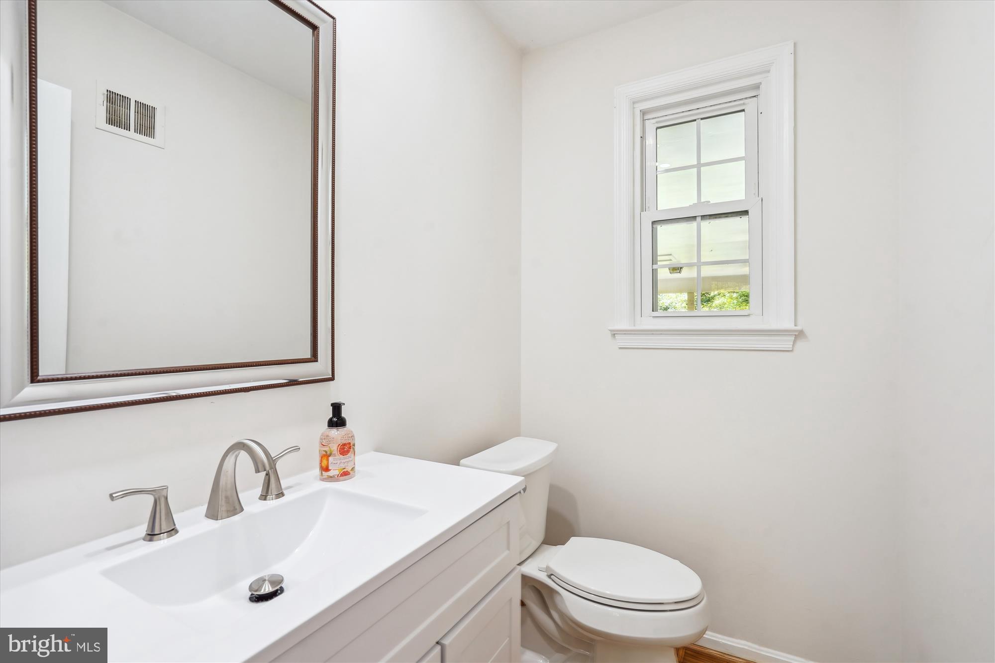 12109 Stirrup Road Reston, VA 20191 - Photo 20 of 52 a bathroom with a toilet a sink a mirror and a window