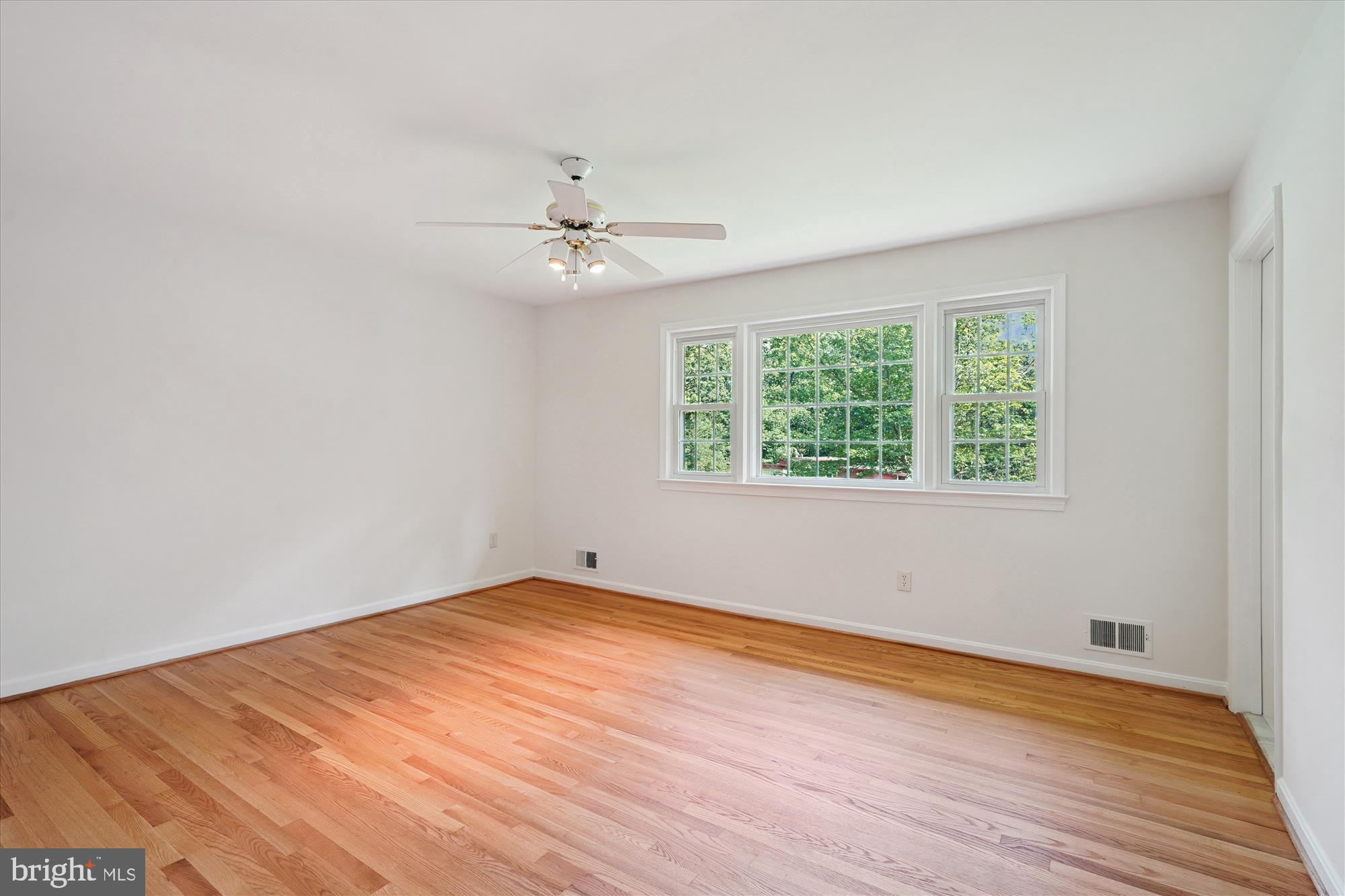 12109 Stirrup Road Reston, VA 20191 - Photo 31 of 52 an empty room with wooden floor chandelier fan and windows