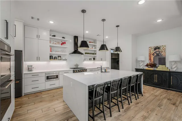 a kitchen with stainless steel appliances kitchen island granite countertop a table chairs stove and refrigerator