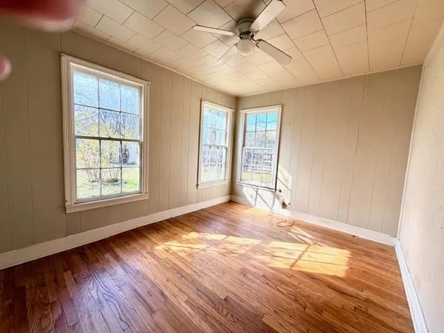 a view of an empty room with a window and wooden floor