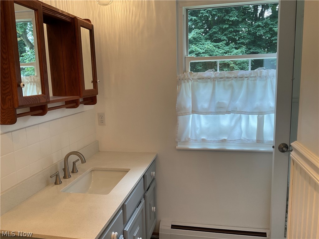 5360 Chapel Road Madison, OH 44057 - Photo 14 of 34 Bathroom featuring a baseboard radiator, vanity, and backsplash