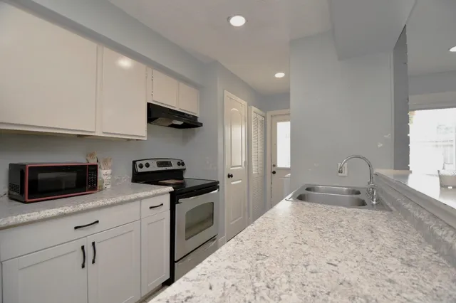 a kitchen with granite countertop a sink stainless steel appliances and white cabinets