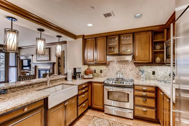 a kitchen with stainless steel appliances granite countertop a sink a stove and a wooden floors