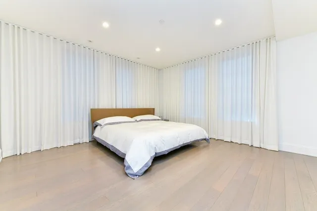 a spacious bedroom with a bed and a curtain