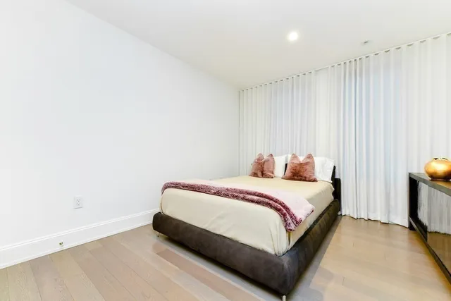 a bed sitting in a spacious bedroom next to a window