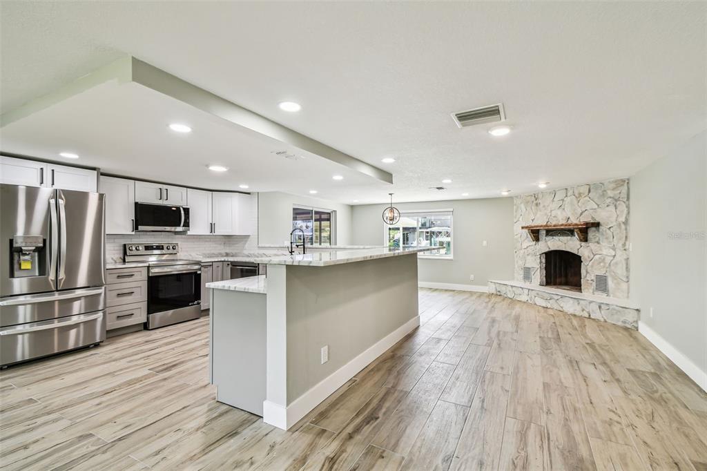 13909 Berkowitz Avenue Hudson, FL 34667 - Photo 15 of 91 a large kitchen with kitchen island a island wooden floor stainless steel appliances and cabinets