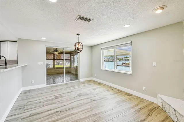 a view of an empty room with wooden floor and window