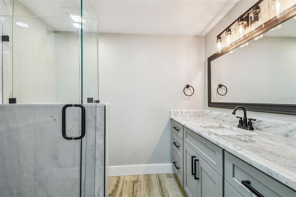 13909 Berkowitz Avenue Hudson, FL 34667 - Photo 32 of 91 a bathroom with a granite countertop sink a mirror and shower