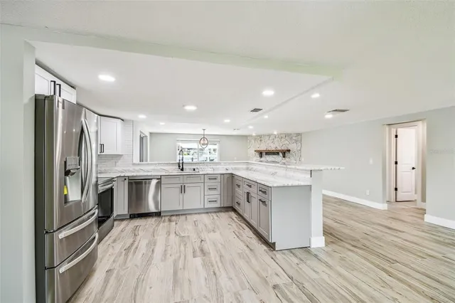 a kitchen with stainless steel appliances granite countertop a stove top oven a sink dishwasher a dining table and chairs with wooden floor