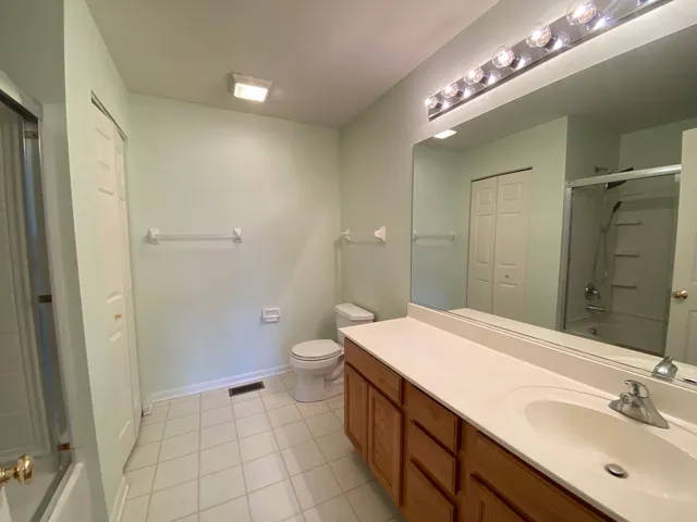 a bathroom with a sink a toilet a mirror and shower