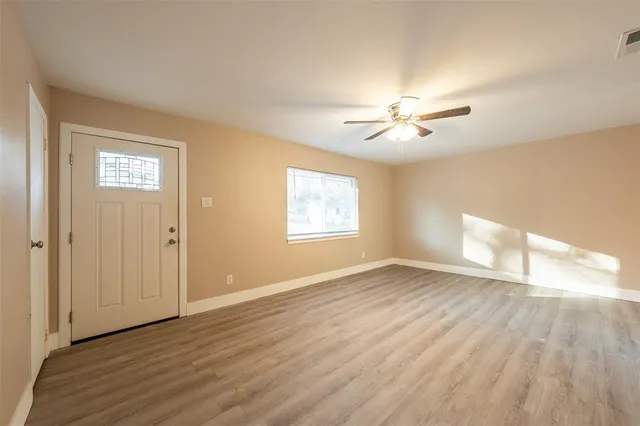 a view of empty room with wooden floor and fan