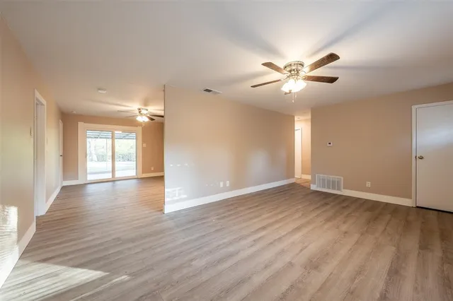 a view of an empty room with window and wooden floor