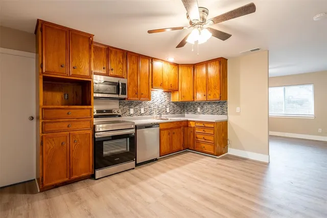 a kitchen with stainless steel appliances granite countertop a stove a sink dishwasher and a refrigerator with wooden floor