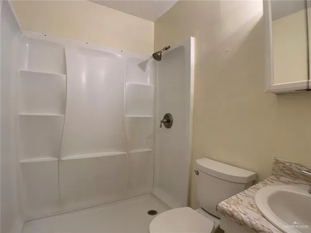 a bathroom with a granite countertop toilet a sink and shower