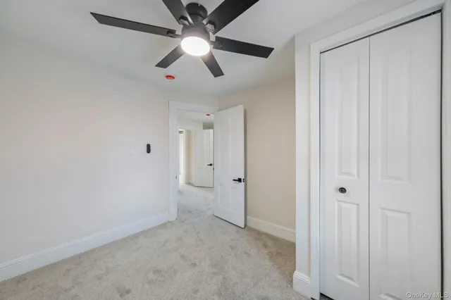 an empty room with closet and a chandelier fan