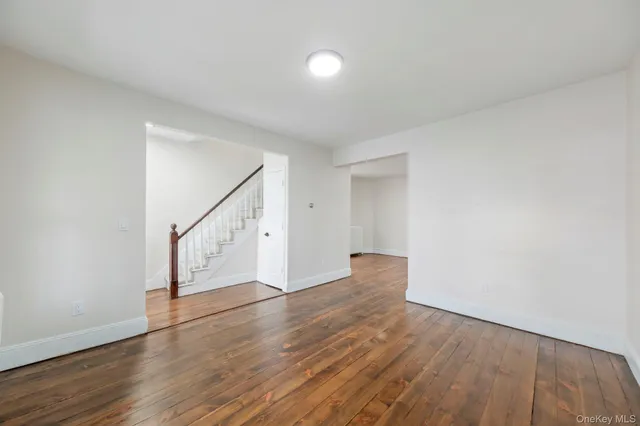 a view of an empty room with wooden floor and stairs