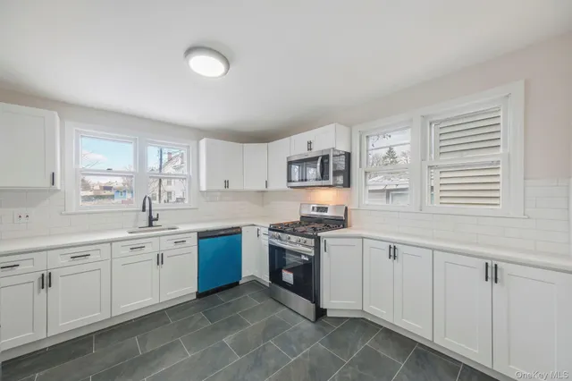 a kitchen with white cabinets and sink