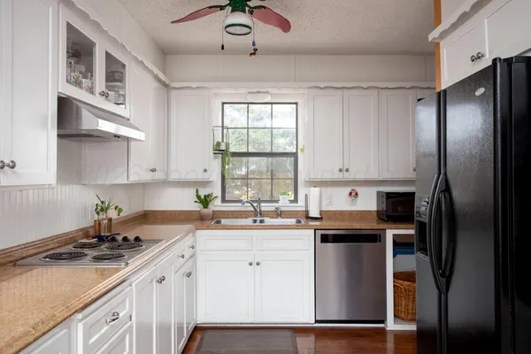 a kitchen with stainless steel appliances granite countertop a sink stove refrigerator and cabinets
