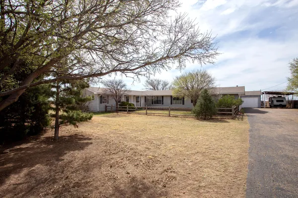 a front view of a house with a yard and a large tree