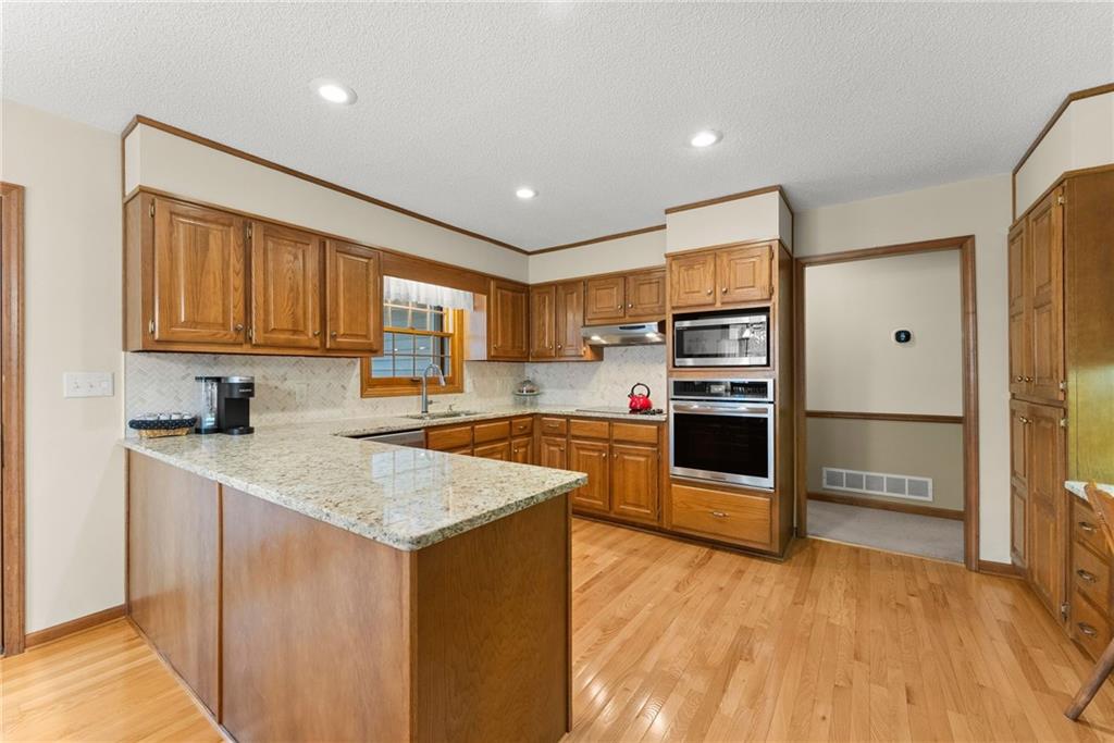 3585 Ridgewood Point Gainesville, GA 30504 - Photo 11 of 41 a kitchen with stainless steel appliances granite countertop a stove top oven a sink dishwasher and a refrigerator with wooden floor