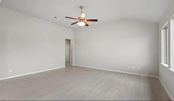 an empty room with windows and chandelier fan