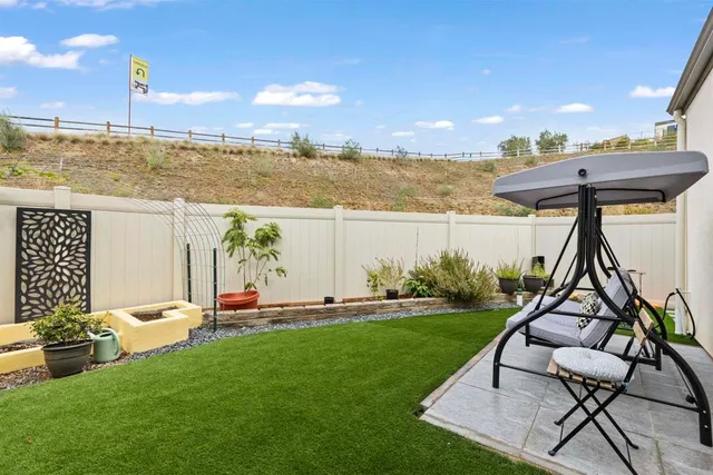 a view of a patio with chairs and plants with wooden fence