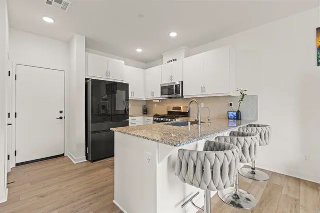 a kitchen with stainless steel appliances granite countertop a refrigerator a stove a sink a microwave and island with wooden floor