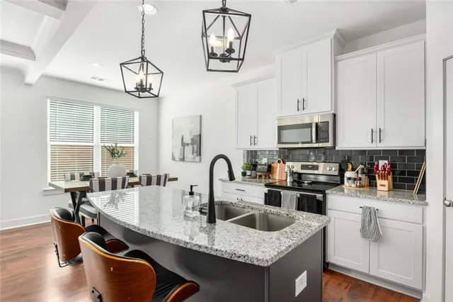 a kitchen with stainless steel appliances granite countertop a sink a stove and cabinets